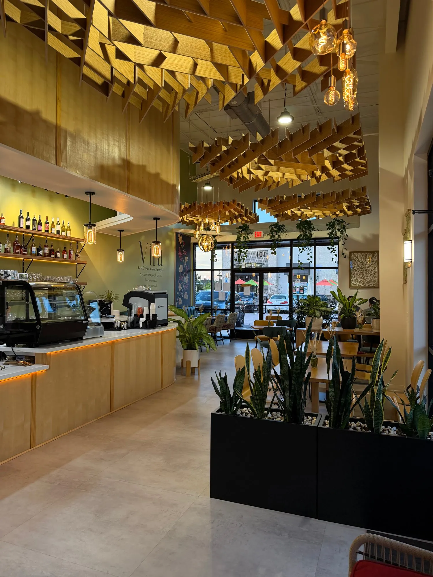 The long bar counter and pastry case under the wooden ceiling