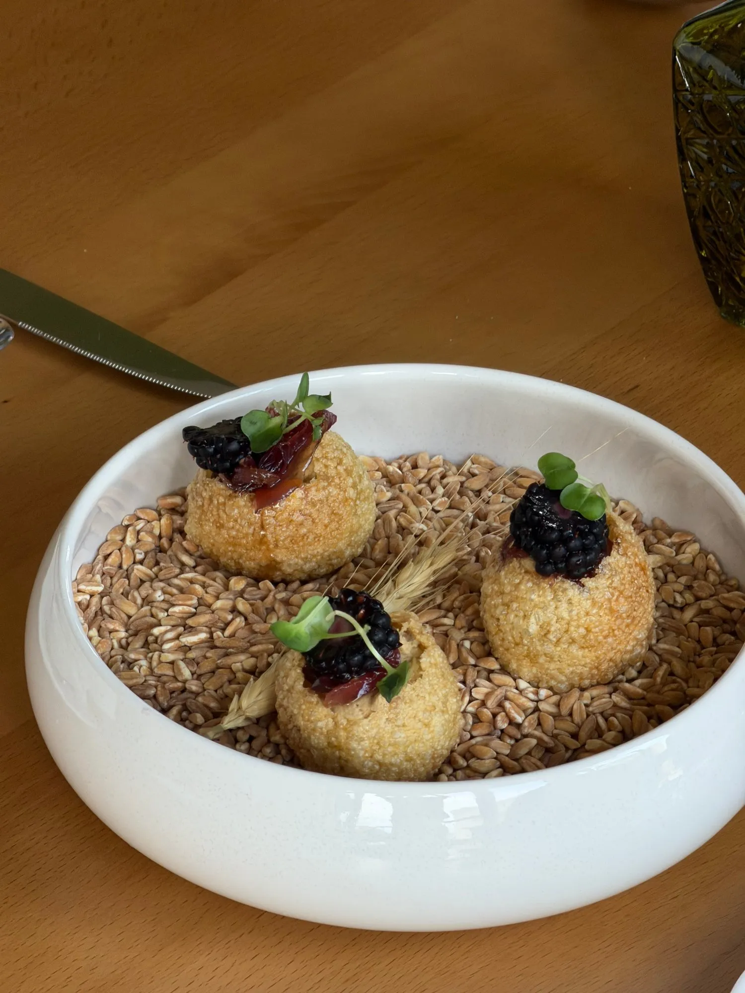 Three rounds of chicken pâté topped with blackberries and onion confit, on a bed of grain