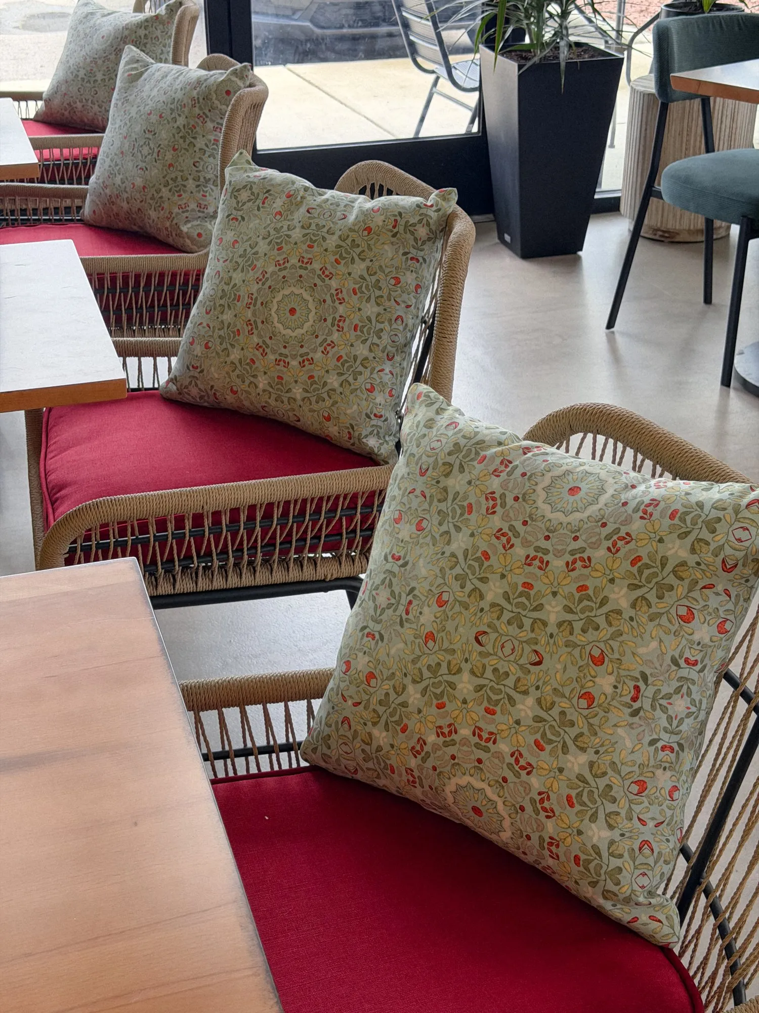 Embroidered cushions on red-seated rattan chairs