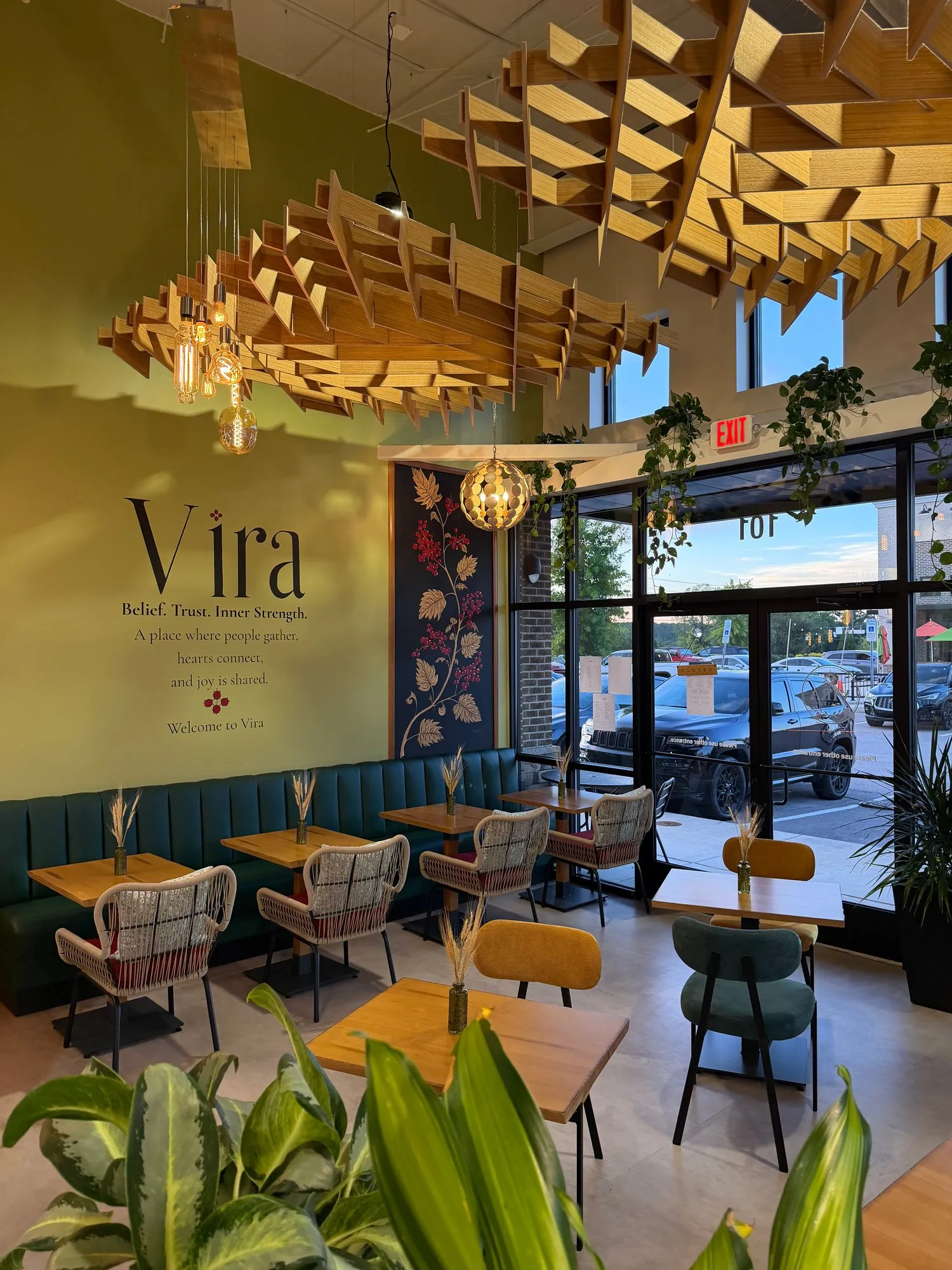 The dining room set for service: tables along the teal banquette under the Vira wall