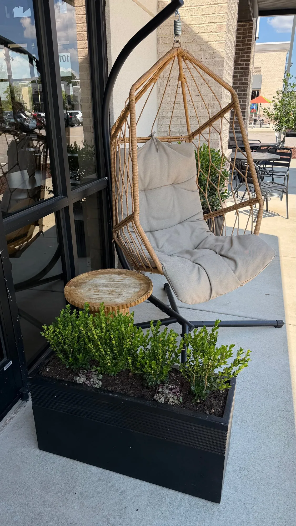 A rattan hanging chair on the patio, by the front windows