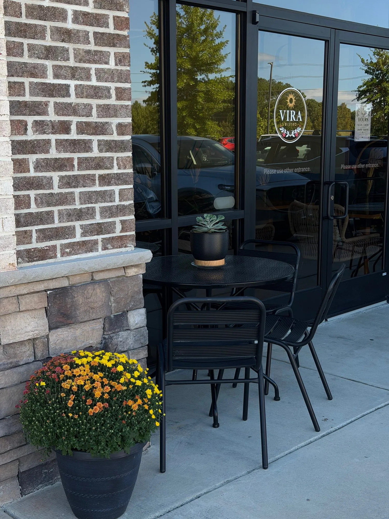 Bistro tables on the patio, beside a pot of autumn mums