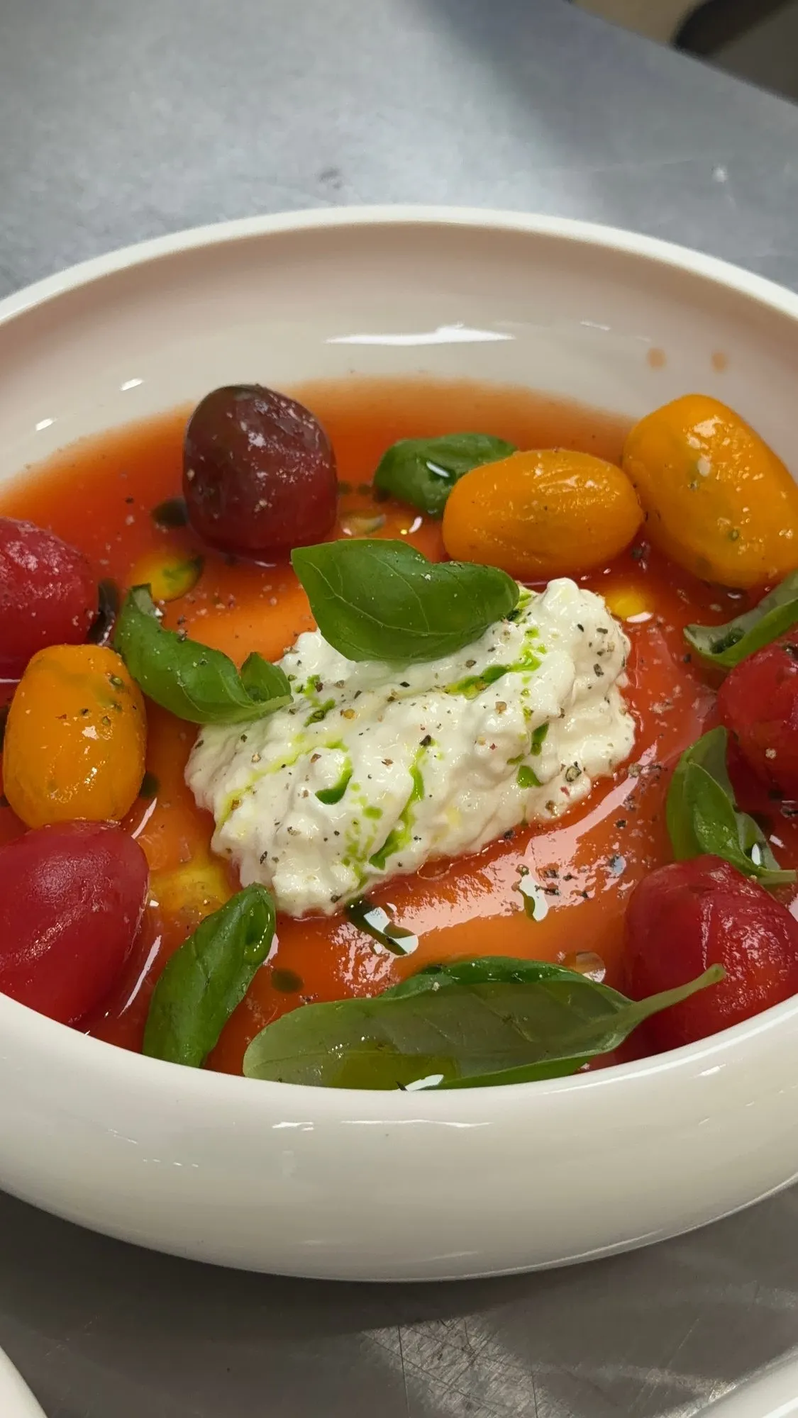 Heirloom tomatoes in their juices around a mound of stracciatella and basil
